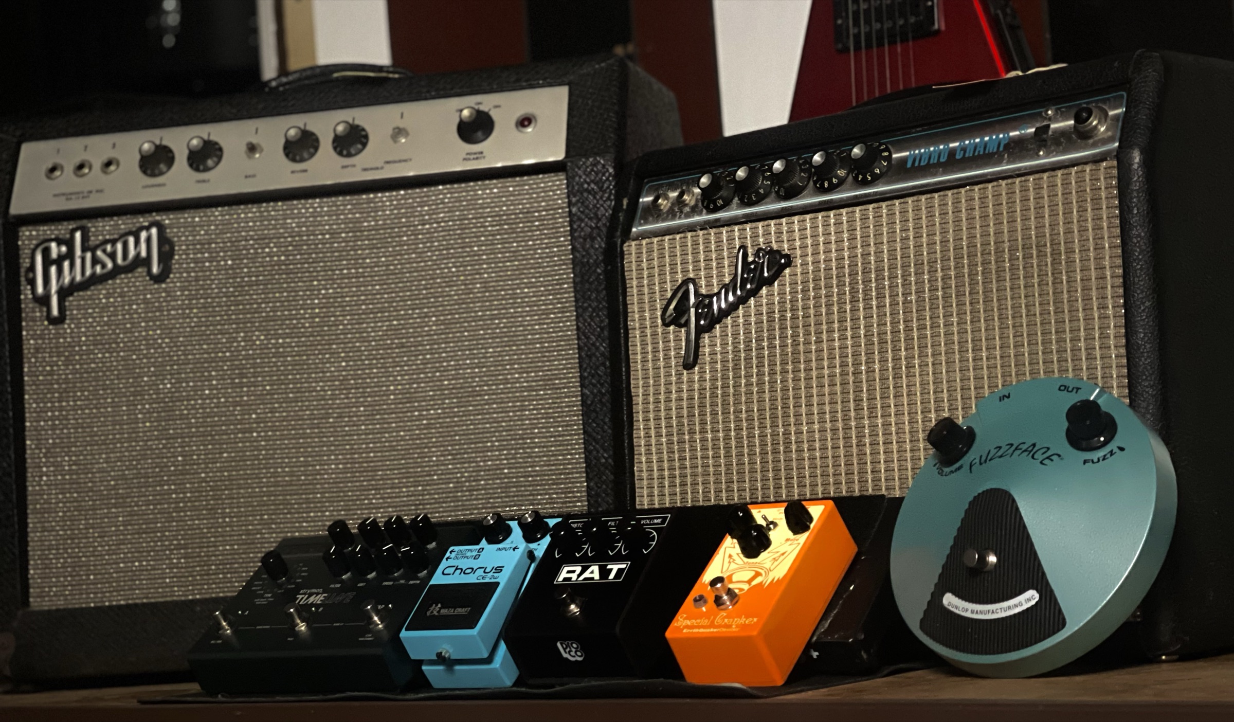 A pedalboard in front of vintage Gibson and Fender amplifiers at Allen Music